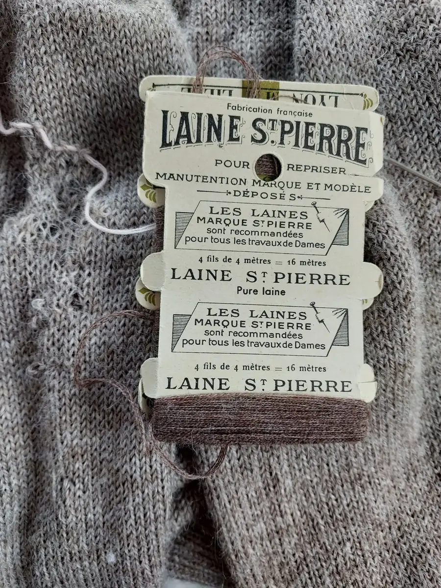 Carte de laine à repriser Laine St Pierre posée sur un pull gris à raccommoder